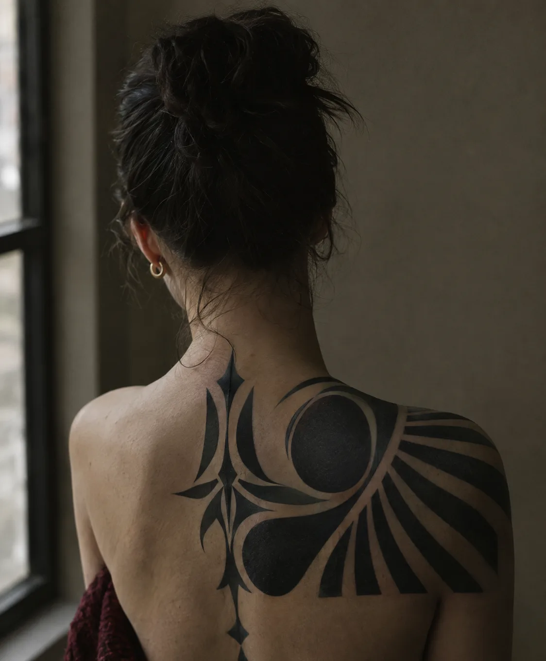 A healed blackwork ornamental piece across a shoulder and upper back